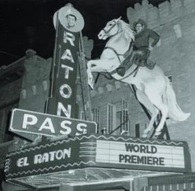A historical black-and-white image of a movie theater marquee featuring a cowboy on a leaping horse, advertising a world premiere.