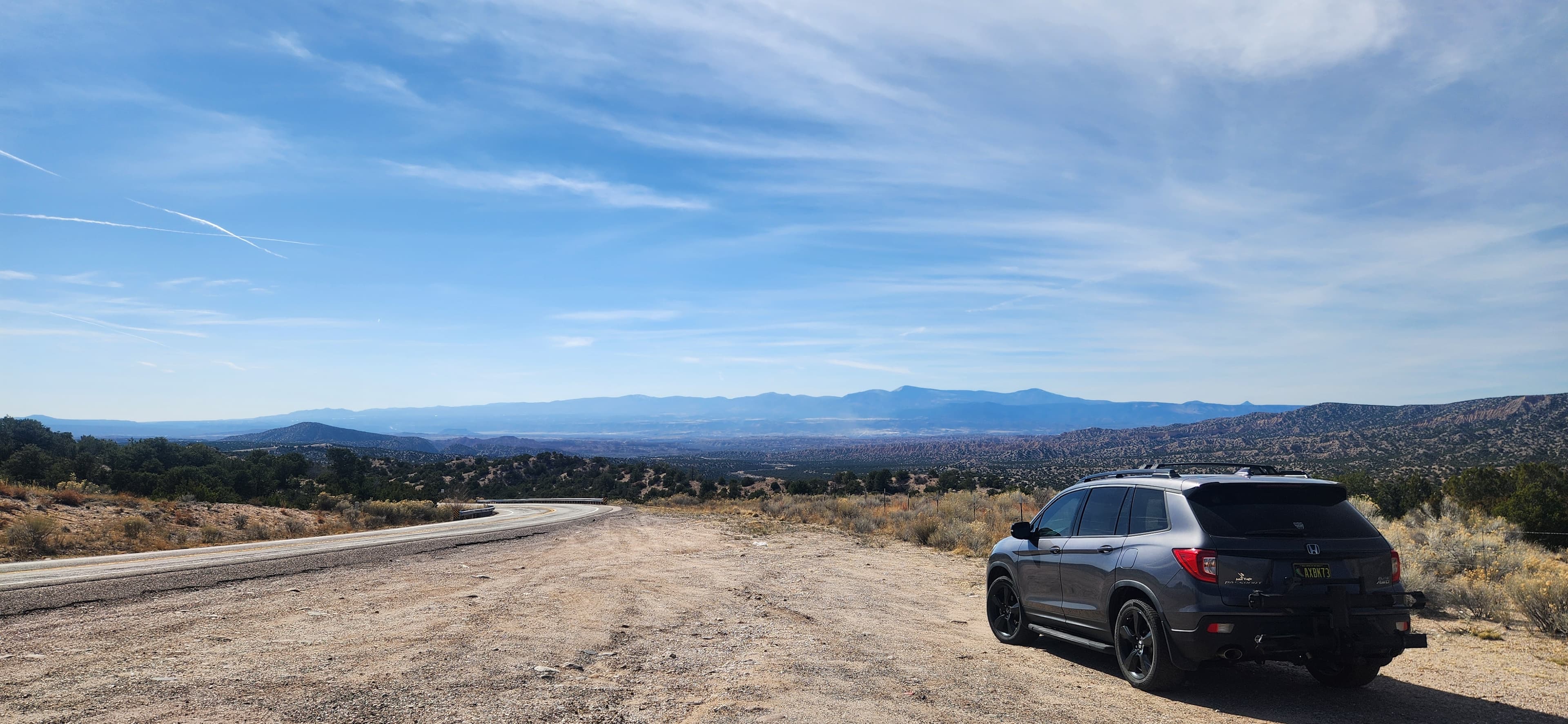 A black SUV parked on a gravel road with a vast landscape and blue sky in the background. A black SUV parked on a gravel road with a vast landscape and blue sky in the background.
