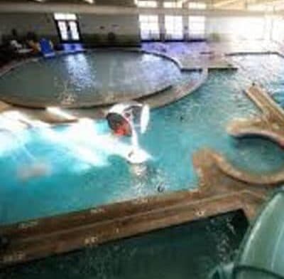 An indoor swimming pool with circular and curved sections and a water slide.