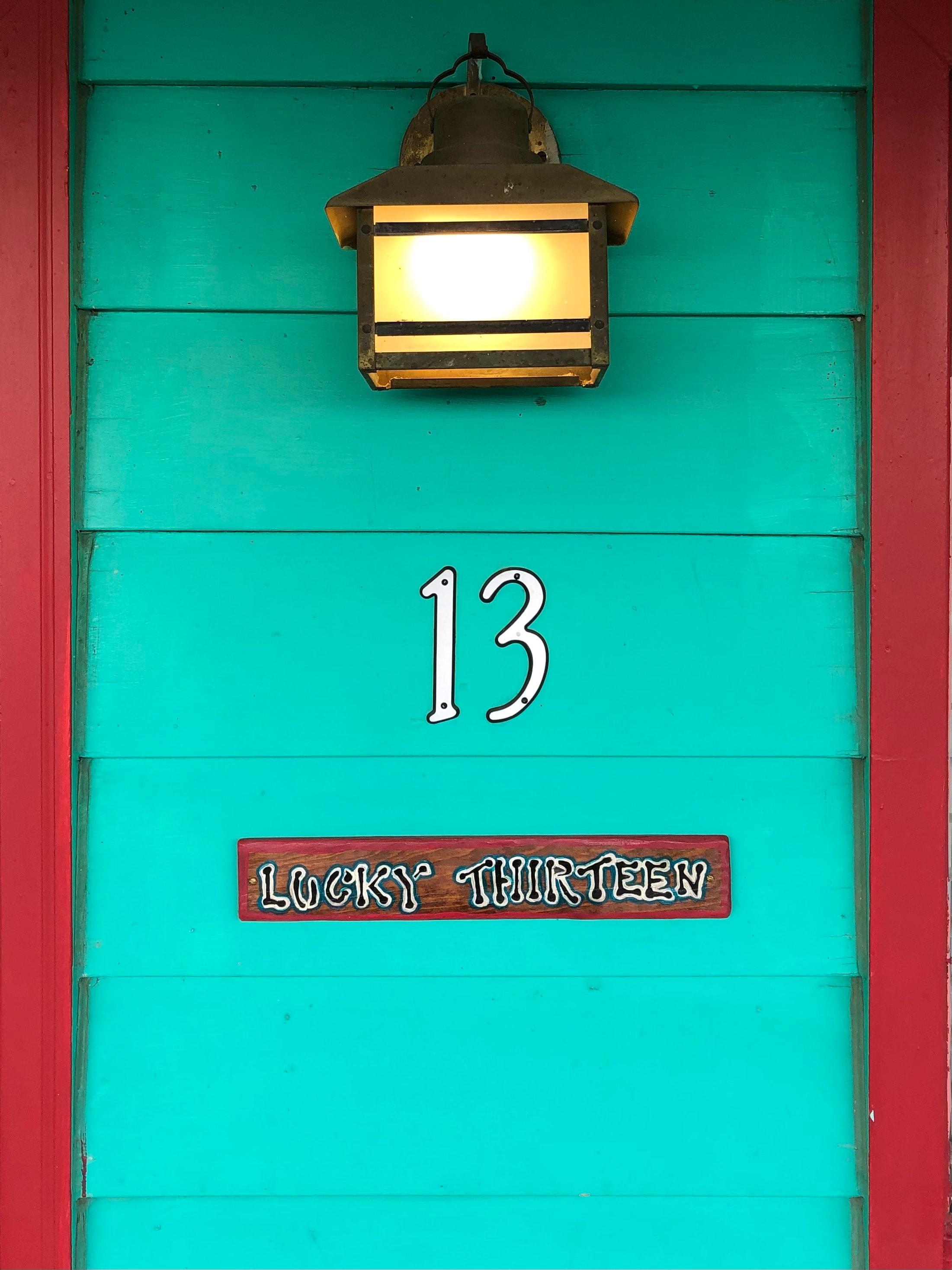 A turquoise door features the number 13 and a sign reading "Lucky Thirteen."