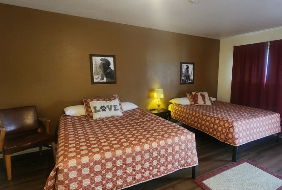room with a chair, two beds, and a lamp
