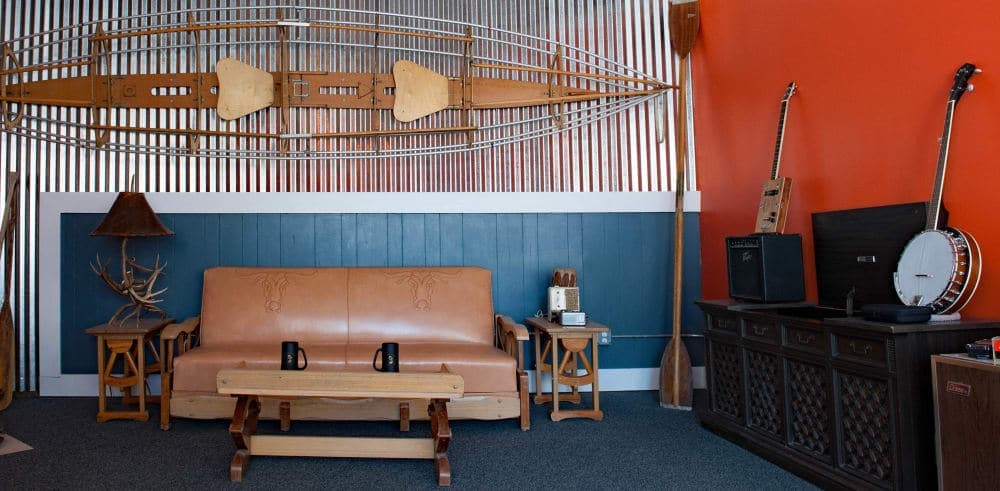A cozy indoor space featuring a leather sofa, wooden furniture, and musical instruments against a colorful wall.