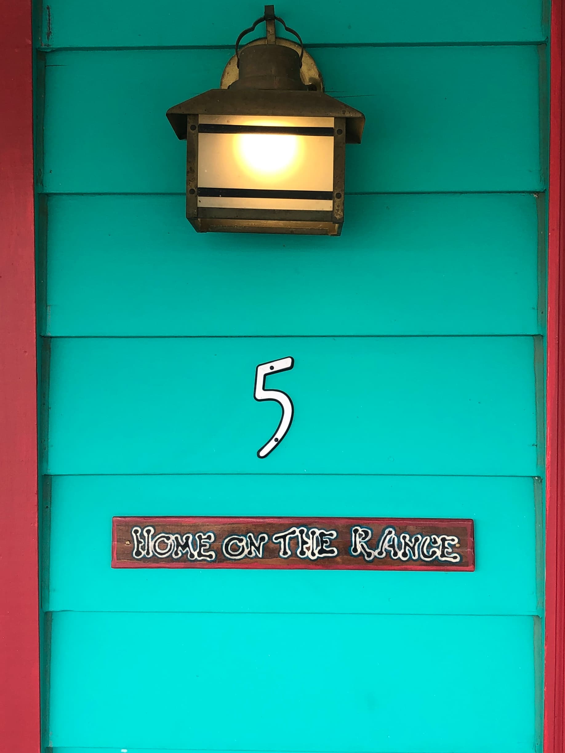 A turquoise wall features a light fixture, the number 5, and a sign reading "Home on the Range."