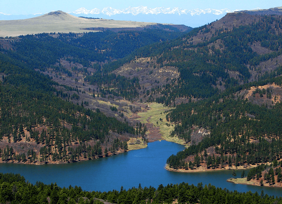 A serene landscape featuring a winding river surrounded by lush green hills and distant snow-capped mountains.