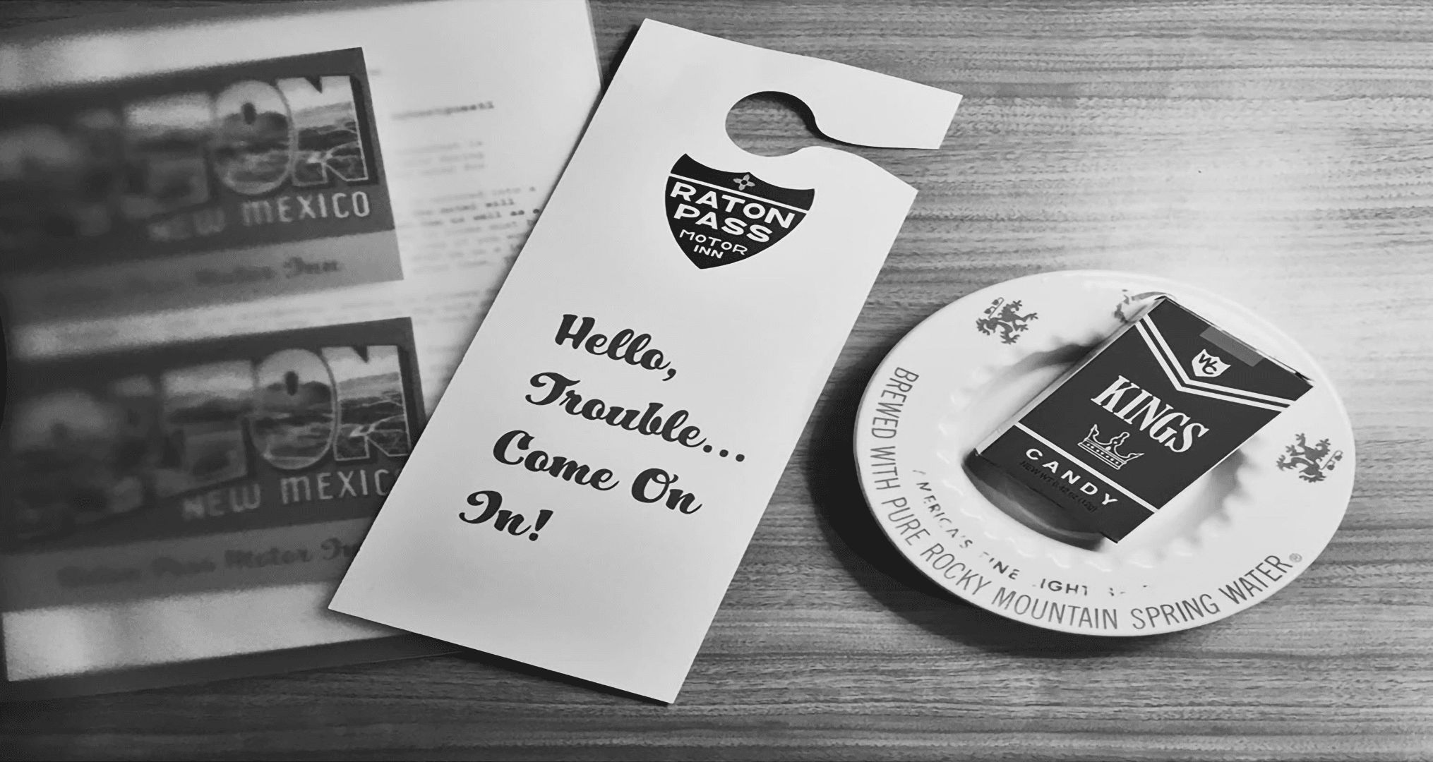 A door hanger from Raton Pass Motor Inn beside a plate with a box of Kings candy.